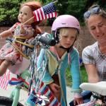 Imogen Resneck, 4, and Jamie Buehner finish up decorating a bike outside the Douglas Public Library on July 3, 2021. Resnecks doll, Robbie, was bound to the bike like an amber-haired figurehead because she wanted to go to the parade, Resneck said. (Ben Hohenstatt / Juneau Empire)