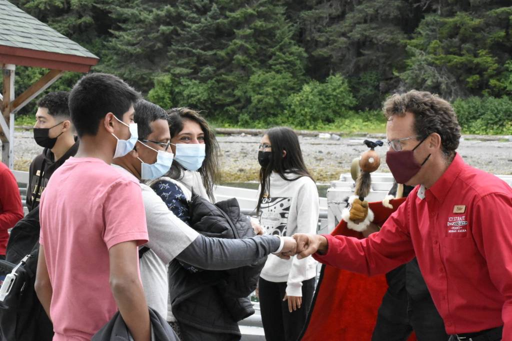 Tyler Hickman, senior vice president of Icy Strait Point, greets members of the Nambiar family from Fort Lauderdale, Florida, the first visitors to Hoonah to come off a cruise ship in over a year. Alaska Native singers and dancers met passengers as they disembarked. (Peter Segall / Juneau Empire)