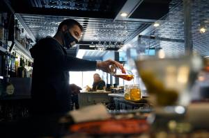In this April 6 photo, bartender Denis Angelov pours drinks at Tin Pan Alley restaurant in Provincetown, Mass. A study of a large coronavirus outbreak in Provincetown suggests the amount of virus in fully vaccinated people was as great as the viral load in unvaccinated people. Health officials released the study Friday, July 30, 2021, saying it explains their call this week for vaccinated people return to wearing masks indoors in parts of the U.S. where the delta variant of the coronavirus is fueling infection surges. The study focused on an outbreak this month in Provincetown, a seaside tourist spot located in the Massachusetts county with the state's highest vaccination rate. (AP Photo/Steven Senne)