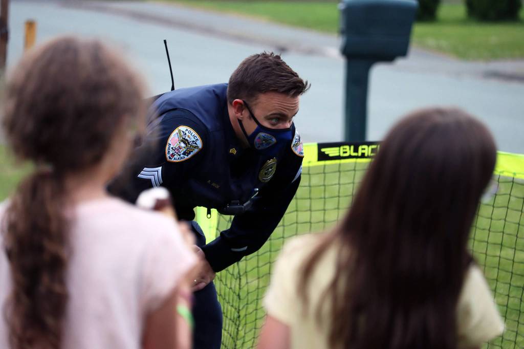 Children look on while Sgt. Ben Beck minds a goal during a pick-up, front yard soccer game during National Night Out. (Ben Hohenstatt / Juneau Empire)