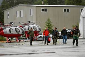 Ketchikan Volunteer Rescue Squad personnel land and disembark from a Hughes 369D helicopter on Thursday, Aug. 5, 2021, at Temsco Helicopters Inc in Ketchikan, Alaska. The KVRS, U.S. Coast Guard, Alaska State Troopers and U.S. Forest Service responded to a radio beacon alert from a downed Southeast Aviation de Havilland Beaver float plane that was carrying five passengers from the Holland America Line cruise ship Nieuw Amsterdam, according to Coast Guard, Holland America and KVRS information. The sightseeing plane crashed Thursday in southeast Alaska, killing all six people on board, the U.S. Coast Guard said.  (Dustin Safranek / Ketchikan Daily News)