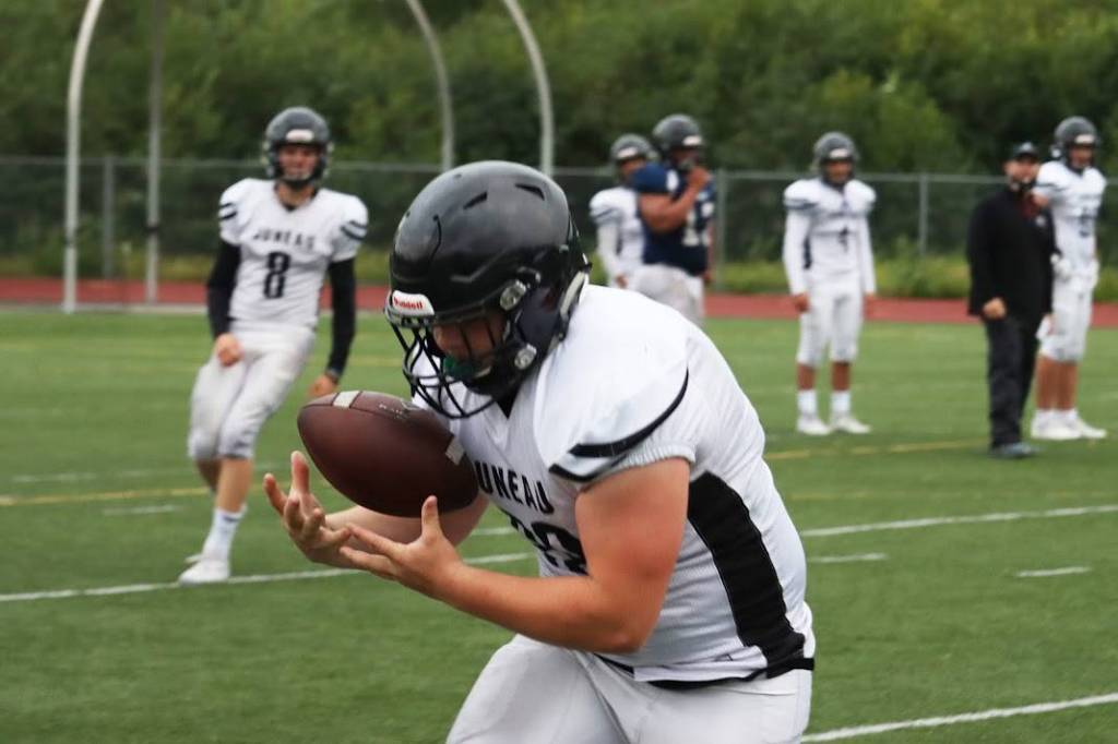 Ben Hohenstatt/Juneau Empire 
Hunter Derr, who plays for the Juneau Huskies, secures a pass from quarterback Noah Chambers, during a Tuesday evening practice outside Thunder Mountain High School.