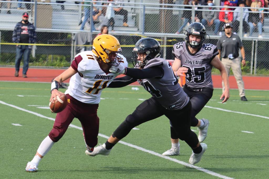 Wyatt Harvey (14) and Brandon Campbell (65) pursue Dimonds quarterback. Campbell was responsible for a key goal-line stop for Juneau in Saturdays win. (Ben Hohenstatt / Juneau Empire)