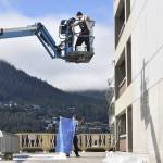 Artists work to hang a 60-by 25-foot mural depicting Elizabeth Kaaxgal.aat Peratrovich on the south wall of the Marine Parking garage on Aug. 30. (Peter Segall/Juneau Empire)