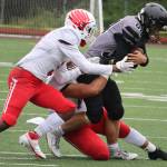 Juneau's Wallace Adams, a senior, trudges forward while draped in East Anchorage defenders. (Ben Hohenstatt / Juneau Empire)