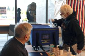 In this Juneau Empire file photo, voter Maralee Guiher drops off her ballot during the City and Borough of Juneau Municipal Election on Oct. 6, 2020. The city announced Wednesday it was looking to hire election workers for this year's city elections. (Ben Hohenstatt / Juneau Empire file)