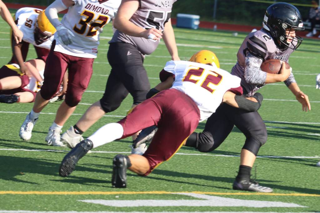 Kadin Messmer, right, runs the ball during a football game against Dimond High School on Aug. 21, 2021. Messmer scored a touchdown during last weeks away game against Service High School. (Ben Hohenstatt / Juneau Empire File)