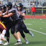 Lucas White (21) and two other Huskies take down a player from Dimond High School on Saturday, Aug. 21. Juneau coach Rich Sjoroos said solid tackling by White and others played a major role in the Huskies 27-14 win against Bartlett High School. (Ben Hohenstatt / Juneau Empire File)