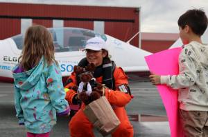 Amelia Conrad, 4, presents Zara Rutherford with a stuffed moose donning aviator goggles while Mclain Patterson, 7, holds a sign reading Fly Zara Fly! at Ward Air. Rutherford is flying her way around the world in pursuit of the Guinness world record for youngest woman solo pilot to circumnavigate the world. (Ben Hohenstatt / Juneau Empire)
