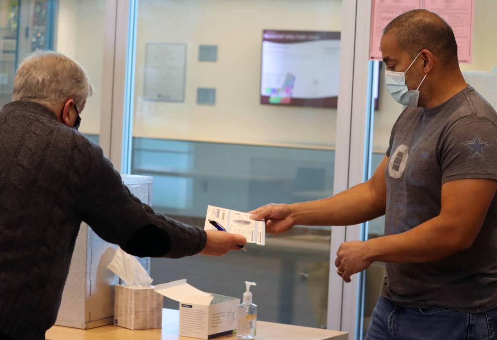 After checking a ballot for a signature and identifier, election official Jack Chenoweth hands a ballot back to James Jenkins on Tuesday. Chenoweth said election officials had caught several ballots that were not properly filled out before they were cast. Jenkins ballot was not among those. (Ben Hohenstatt / Juneau Empire)