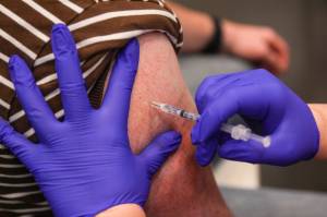 A Juneau resident receives a flu shot while getting a booster shot for the Pfizer coronavirus vaccine at Centennial Hall on Oct. 2, 2021. More than 1,300 Juneau residents received booster shots at the clinic and about half of those people also received a flu shot. (Michael S. Lockett / Juneau Empire)