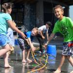 David Kimbrough, 7, right, Clayton Haywood, 6, center, and Kyla Belcourt, 8, play in sprinklers set up during the RALLY program at Harborview Elementary School on Wednesday, June 26, 2019. RALLY provides before- and after-school care to families with school-age children and offers care during school breaks. Recently, some parents have complained that the price of the program is too high. Meanwhile, school officials say RALLY routinely loses money and that changes are needed to make it more sustainable. (Michael Penn / Juneau Empire File)