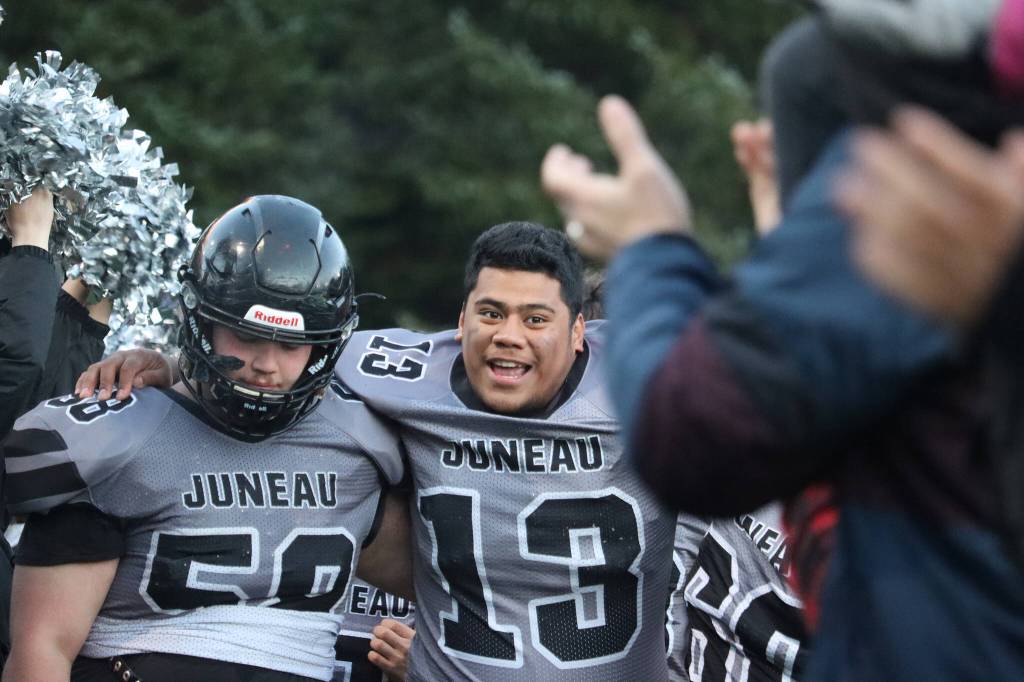 Senior Mathias Wiederspohn (58), a lineman, helps junior Sam Sika (13), a lineman, off the field and through a tunnel of fans and cheerleaders following the Huskies big win. (Ben Hohenstatt / Juneau Empire)