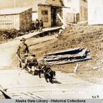 This photo from the Capt. George H. Whitney Photograph Collection shows a man, with wheelbarrow cart and two dogs in harness, transports beer barrels along boardwalk; pedestrians, buildings, and sign for Coon's Drugstore in background in Juneau in 1886. Juneau and Douglas' breweries were the subject of the Gastineau Channel Historical Society's award-winning newsletter. (William Howard Case/ Alaska State Library - Historical Collections)