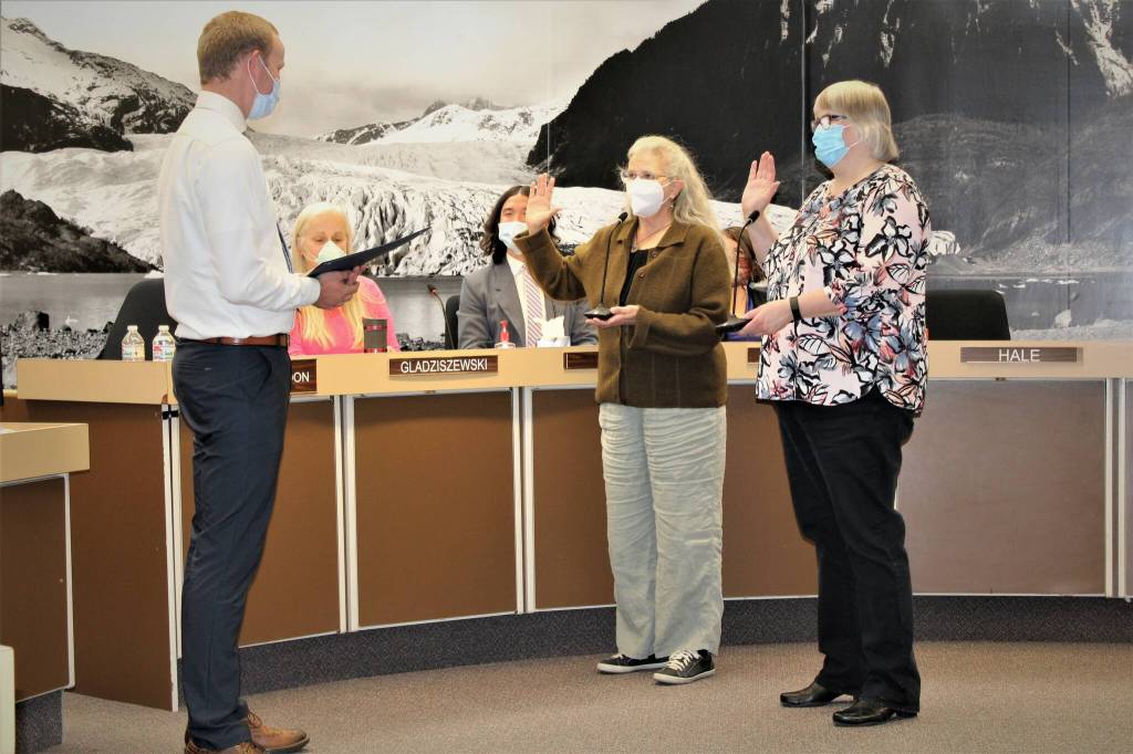 Municipal attorney Robert Palmer, left, administers the oath of office to Mayor Beth Weldon, right, and Assembly member Michelle Bonnet Hale, center, on Monday, Oct. 25. Both Weldon and Hale are beginning second terms after being re-elected in this months election. (Dana Zigmund/Juneau Empire)