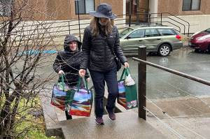 Juneau School District food program administrative assistant Catherine Pusich, front, and supervisor Adrianne Schwartz deliver free groceries to the winner of a giveaway linked to a recent meals survey for the district on Oct. 27, 2021. (Michael S. Lockett / Juneau Empire)