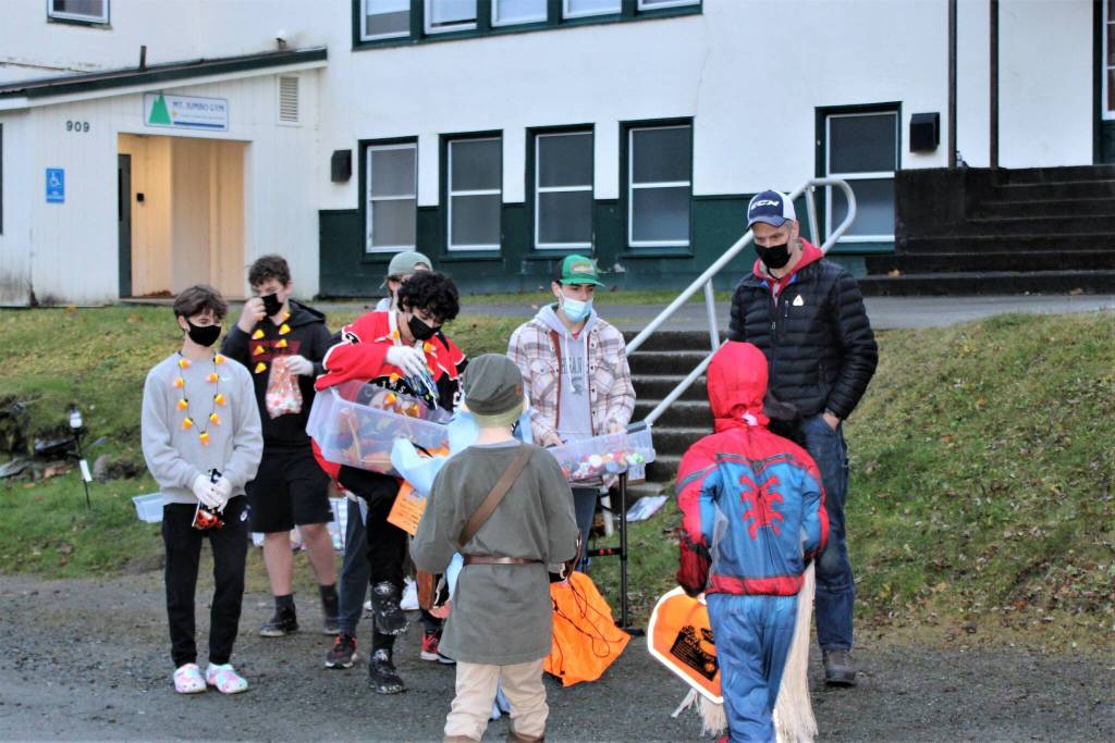 Members of the Juneau-Douglas High School: Yadaa.at Kale hockey team hand out candy in front of the Mount Jumbo Gym on 4th Street in Douglas on Sat. Oct. 30. Most trick-or-treaters stayed in the car to collect treats at the drive-through trunk or treat sponsored by the Douglas Fourth of July Committee. But, a few neighborhood kids walked through the line. Organizers said that about 250 kids came through the event during the first hour. (Dana Zigmund/Juneau Empire)