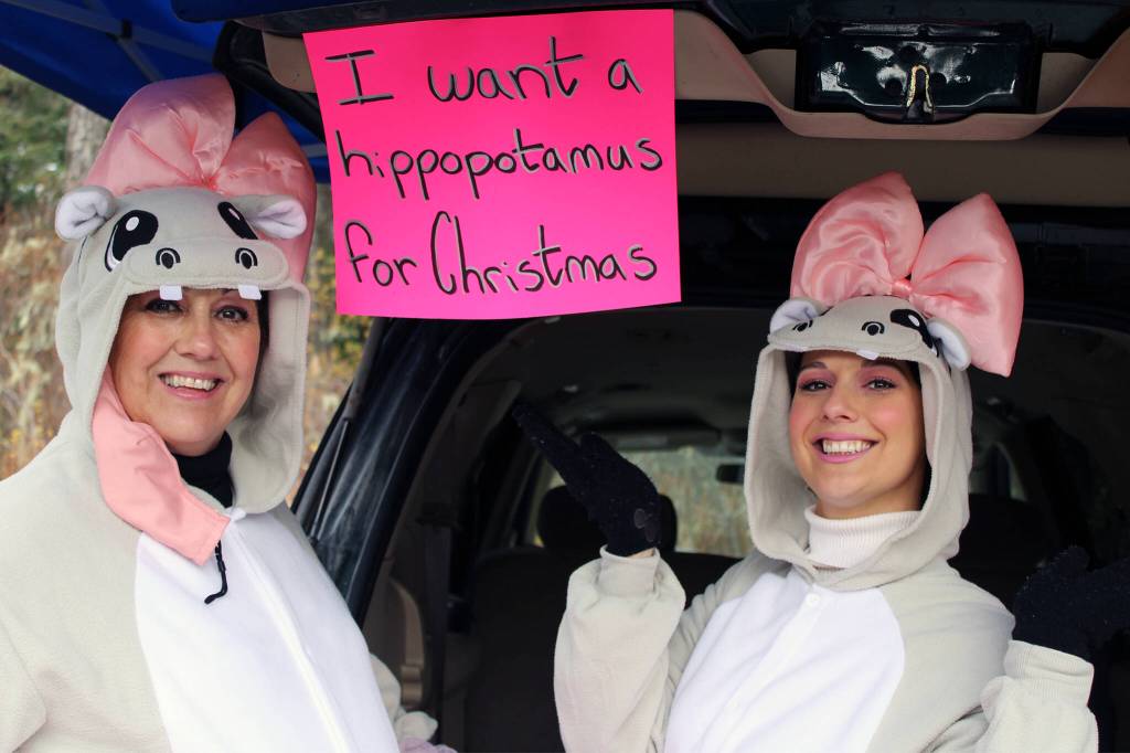 Laura, left, and Brittany, right, Eubanks handed out candy Saturday, Oct. 30 at Chapel by the Lake during the trunk or treat event. It may be Halloween weekend, but their sign made it clear they are eyeing the upcoming holiday season. (Dana Zigmund/Juneau Empire)