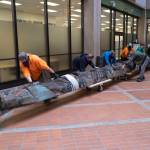 Workers move the Wooshkeetaan Kootéeyaa (totem pole) through the state office building on Oct. 15. After a few weeks of laying flat so that it can adjust to the climate inside the building, the totem pole will be raised and a celebration will be planned. (Michael Penn / For the Jundeau-Douglas City Museum)