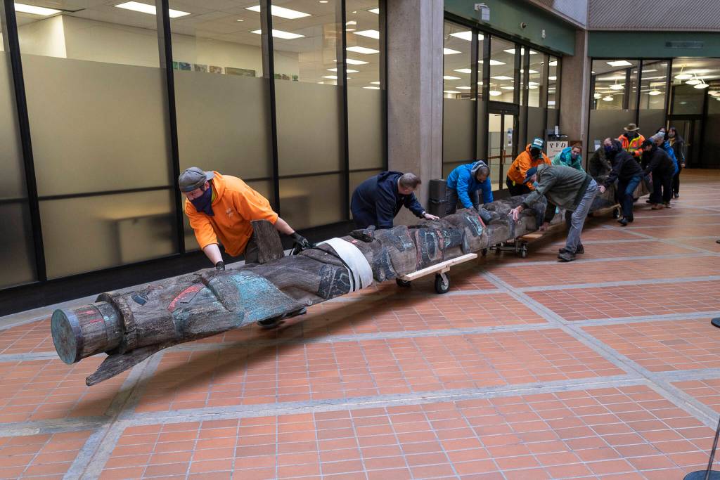 Workers move the Wooshkeetaan Kootéeyaa (totem pole) through the state office building on Oct. 15. After a few weeks of laying flat so that it can adjust to the climate inside the building, the totem pole will be raised and a celebration will be planned. (Michael Penn / For the Jundeau-Douglas City Museum)