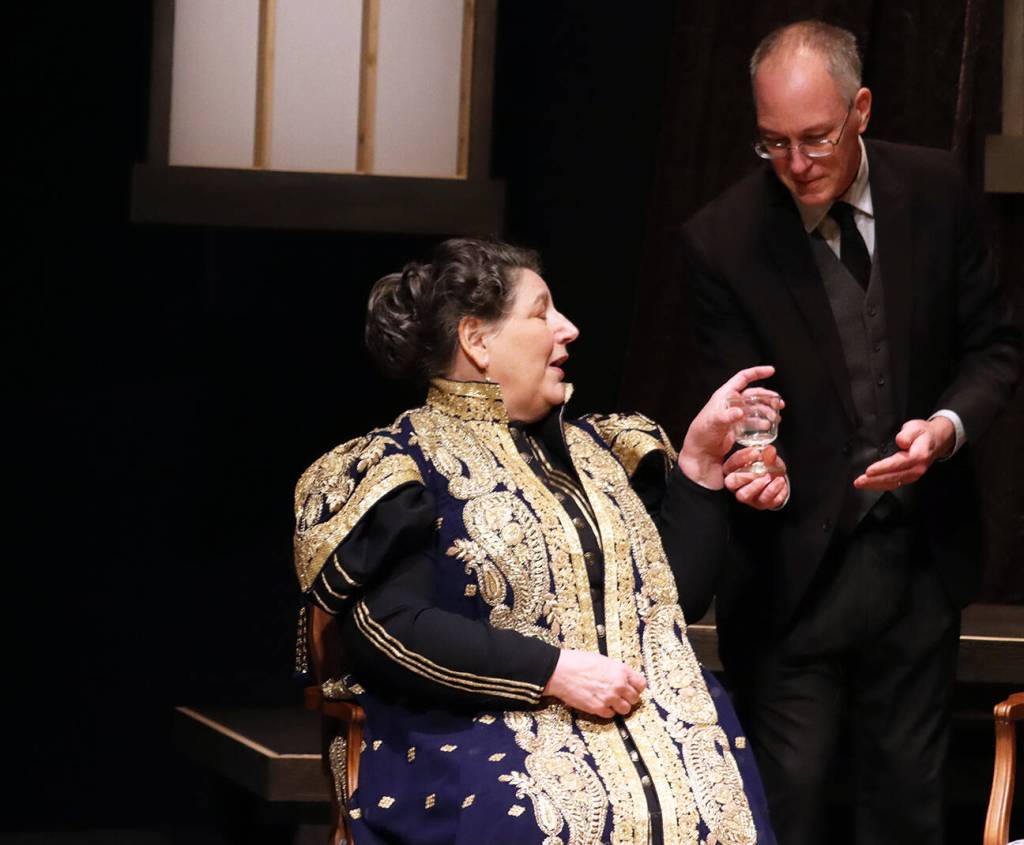 Edgar (Pat Minik) serves a beverage to Sybil Birling (Becky Orford) during dress rehearsal for An Inspector Calls. (Ben Hohenstatt / Juneau Empire)