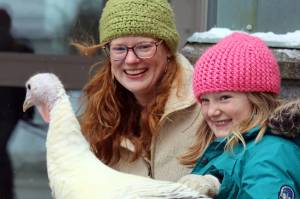 Marie and Molly Heidemann smile as molly pets Penny the turkey on Saturday at the Juneau-Douglas High School: Yadaa.at Kalé IGNITE Clubs second annual turkey shoot event. The photo shoot raised money to support the club, which hopes to build a small barn at the school. (Ben Hohenstatt / Juneau Empire)