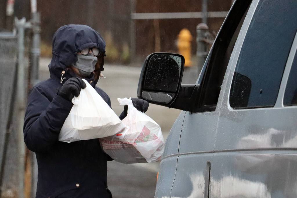 Bridget Vivoda, a volunteer with the Jesuit Volunteer Corps, carries bags of Thanksgiving meals to a vehicle on Thursday. (Ben Hohenstatt / Juneau Empire)