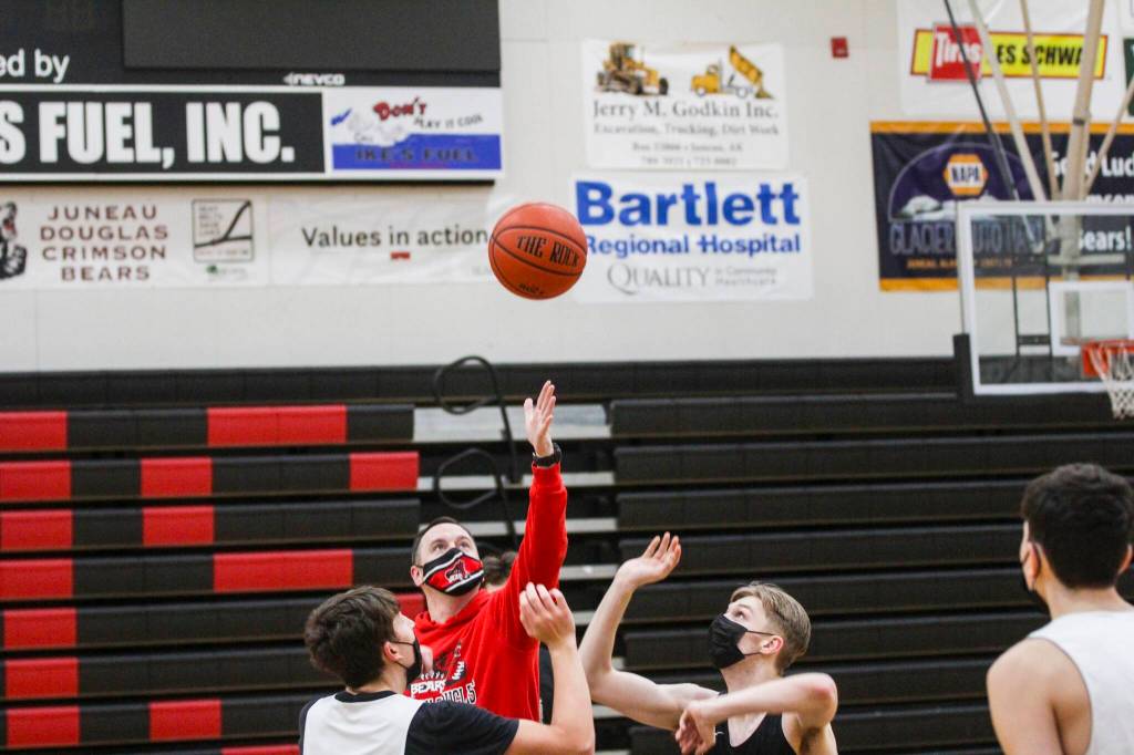 Juneau-Douglas High School: Yadaa.at Kalé varsity boys basketball players Orion Dybdahl, left and Jake Sleppy, right contest a jump ball from Coach Robert Caspersons during a practice on Dec. 14, 2021. (Michael S. Lockett / Juneau Empire)