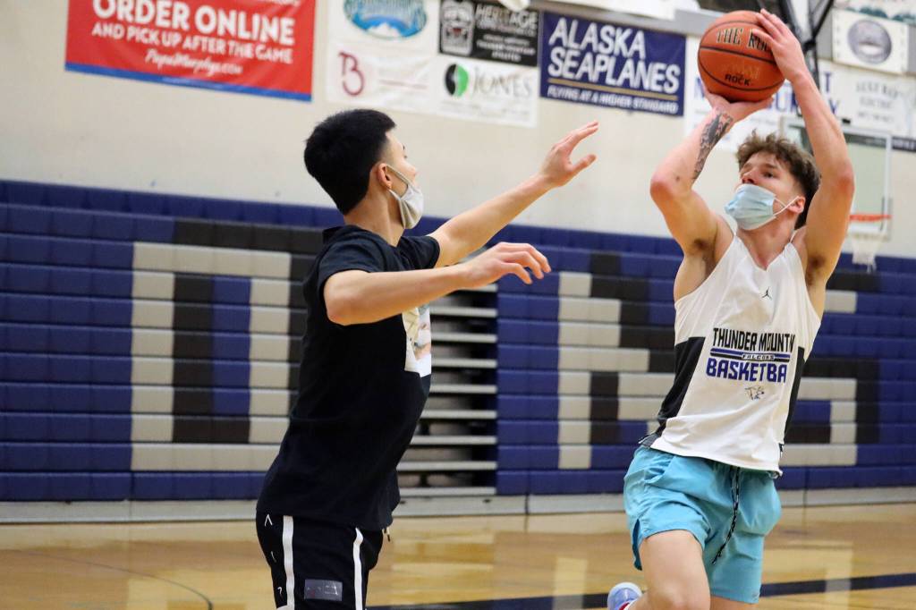 Thomas Baxter, a sophomore, rises for a shot over Bryson Echiverri, a former TMHS standout, during practice. Echiverri, who currently plays for Spokane Community College, was back in the capital city for the holidays and the Thunder Mountain High School alumni game. (Ben Hohenstatt / Juneau Empire)
