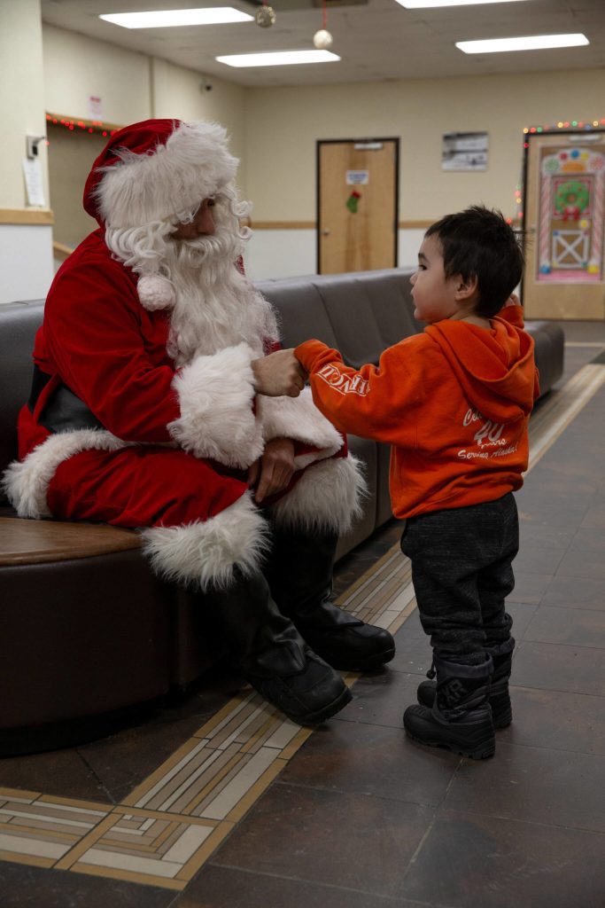 U.S. Marine Corps Gunnery Sgt. Jake Paolucci, Company Gunnery Sgt. of Delta Company, 4th Law Enforcement Battalion, Marine Forces Reserve, fist-bumps a child while dressed as Santa Claus in Kotzebue, Alaska, Dec. 11, 2021. (U.S. Marine Corps / Cpl. Brendan Mullin)