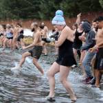 Participants move quickly but gingerly into the water at the 2022 Polar Dip held Saturday. (Ben Hohenstatt / Juneau Empire)