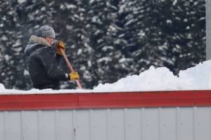 Steven Duke shovels snow from the top of the roof at Don Abel Tool and Equipment Rental on Jan. 7. (Dana Zigmund/Juneau Empire)