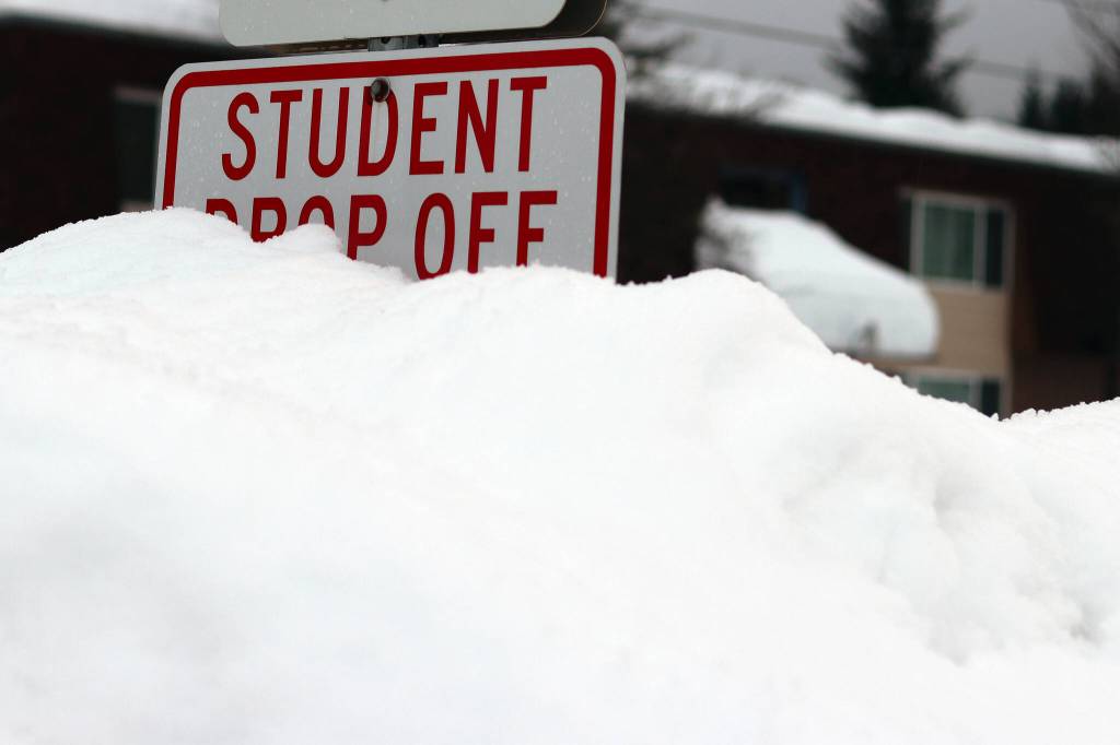 A mound of a snow obscures a student drop off sign near Sít Eetí Shaanàx-Glacier Valley School. School officials announced on Monday that classes were canceled for Tuesday due to weather. (Ben Hohenstatt / Juneau Empire)