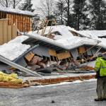 A worker stands outside a collapsed building in Lemon Creek on Tuesday, Jan. 11, 2022, one of two building collapses reported in Juneau amid ongoing rain following heavy snowfall. The City and Borough of Juneau said no injuries were reported and urged building owners to be cautious of snow loads on roofs. (Peter Segall / Juneau Empire)