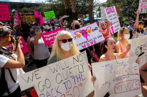 FILE - Participants wave signs as they walk back to Orlando City Hall during the March for Abortion Access on Saturday, Oct. 2, 2021, in Orlando, Fla.  State-by-state battles over the future of abortion in the U.S. are setting up across the country as lawmakers in Republican-led states propose new restrictions modeled on laws passed in Texas and Mississippi even as some Democratic-controlled states work to preserve access.  (Chasity Maynard/Orlando Sentinel via AP, File)