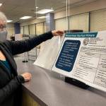 Deborah Moody, an administrative clerk at the Alaska Division of Elections office in Anchorage, Alaska, looks at an oversized booklet explaining election changes in the state on Jan. 21, 2022. Alaska elections will be held for the first time this year under a voter-backed system that scraps party primaries and sends the top four vote-getters regardless of party to the general election, where ranked choice voting will be used to determine a winner. No other state conducts its elections with that same combination. (AP Photo / Mark Thiessen)