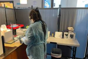 Mina Sanders, a COVID tester with Capstone Clinic, readies for the next group of arrivals at Juneau International Airport on Jan. 31, 2022. (Michael S. Lockett / Juneau Empire)