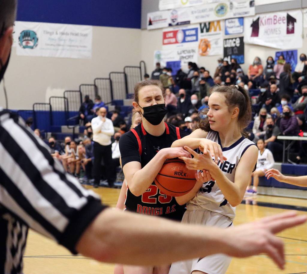 JDHS Ashley Laudert and TMHS Cailynn Baxter scrap for possession of the ball during JDHS 47-37 win at Thunder Mountain High School on Friday night. (Ben Hohenstatt / Juneau Empire)