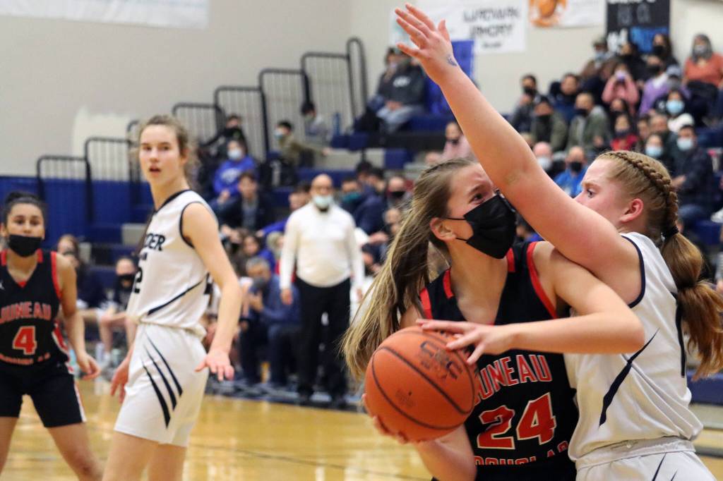 JDHS Mila Hargrave pivots toward the hoop for a tough inside shot while tightly defended by TMHS Sydney Strong. In the background JDHS Kiyara Miller and TMHS Kerra Baxter look on. (Ben Hohenstatt / Juneau Empire)