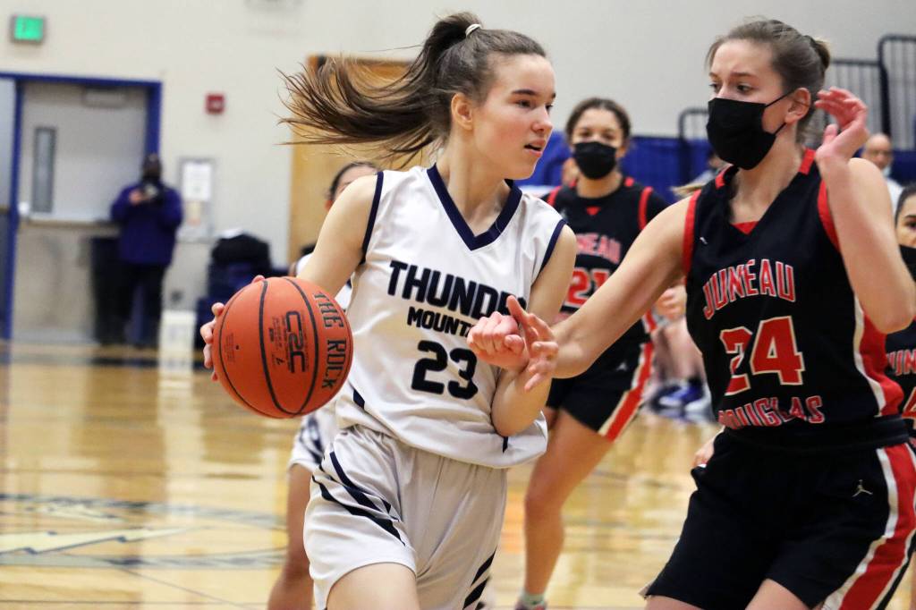 TMHS Cailynn Baxter drives toward the basket while JDHS Mila Hargrave defends. (Ben Hohenstatt / Juneau Empire)