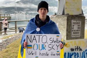 Viktor Tkachenko, who moved to Alaska from Ukraine last year, holds a sign asking NATO for assistance defeating Russian airpower at a protest against the war in Marine Park on Feb. 26, 2022. (Michael S. Lockett / Juneau Empire)