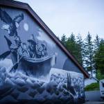 In March 2020, Hydaburg began displacing thousands of gallons of expensive imported heating oil with low-grade waste wood to heat their school buildings. Photo of the school building with the beautiful new mural by Haida artist Andrew Morrison, (Courtesy Photo / Bethany S Goodrich)