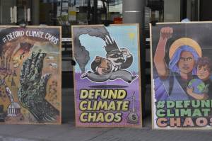 Members of local environmental group 350Juneau and the Women's Earth and Climate Action Network displayed signs in front of the downtown Juneau branch of Wells Fargo on Monday, April 11, 2022, as part of a demonstration urging the company's corporate leadership to cease funding of fossil fuels. (Peter Segall / Juneau Empire)