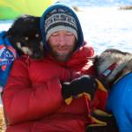 Jessie Holmes takes a break from cooking his dogs a meal to nuzzle with two wheel dogs at the Ophir checkpoint during the Iditarod Trail Sled Dog Race on Wednesday, March 10, 2021. A pack of sled dogs belonging to Holmes, Iditarod veteran and reality TV star killed a family pet in Alaska, officials said. Authorities in Wasilla are investigating a March 30, 2022 incident involving dogs owned by musher Holmes, who finished third in years Iditarod Trail Sled Dog Race and stars in Life Below Zero: Alaska on the National Geographic channel. (Zachariah Hughes/Anchorage Daily News via AP, Pool, File)