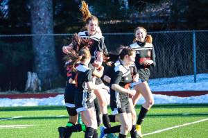 JDHS forward Kyla Bentz, top center, celebrates with her team after scoring on TMHS during a game at Adair-Kennedy Memorial Park on April 12, 2022. (Michael S. Lockett / Juneau Empire)