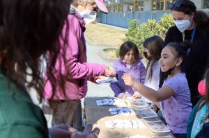 Jiselle Tagaloa, a kindergarten student, accepts payment for a card from Jan Beauchamp. Beauchamp was among those who bought cards' bearing students drawings to support a Ukrainian family living in Washington state. (Ben Hohenstatt / Juneau Empire)