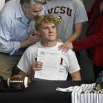 Noah Chambers holds up an agreement to play football at Valley City State University in Valley City, North Dakota, while his father Mike looks on during a signing ceremony at Thunder Mountain High School on Wednesday. Chambers said he was excited to be playing quarterback and was considering a degree in engineering. Im super excited, Ive worked my whole childhood for this, Chambers told the Empire.