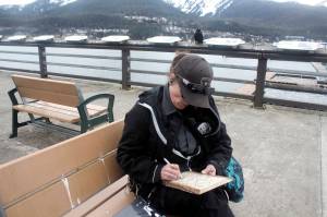 Mark Sabbatini / Juneau Empire 
Amy Purvis, a private security officer whos been a Juneau resident since 2000, sketches a heart and rose for a piece of woodburning art she hopes to sell to tourists this summer on the still mostly empty pier at Marine Park on Friday.