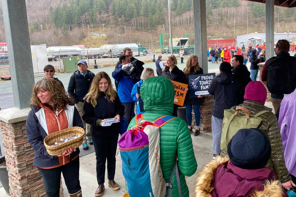 Members of local business organizations greet cruise passengers with maps and other handouts as they disembark from the Norwegian Bliss, the first vessel of the 2022 cruise season, on April 25, 2022. (Michael S. Lockett / Juneau Empire)