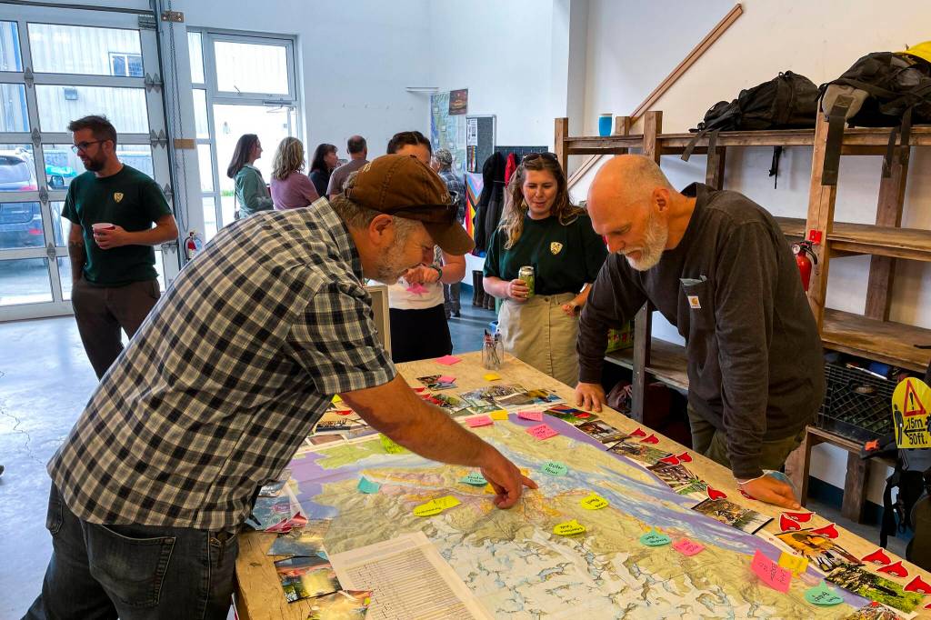 Juneau Parks and Recreation director George Schaaf, left, looks at a map with Trail Mix Inc. board member Chris Meade during the nonprofits annual National Trails Day event in their new office space on June 4, 2022. (Michael S. Lockett / Juneau Empire)